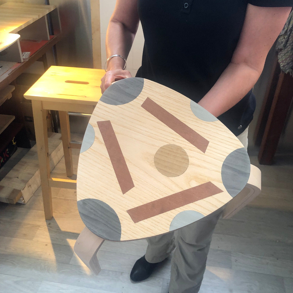 Tabouret en bois décoré avec des motifs géométriques en marqueterie contemporaine, alliant différentes essences de bois dans des teintes naturelles et chaleureuses. Création artisanale réalisée lors d'un atelier de marqueterie à Nancy.