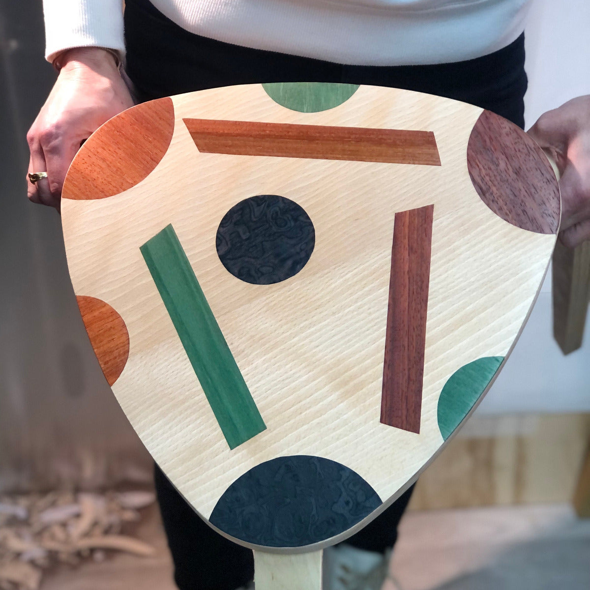 Tabouret en bois orné de motifs colorés en marqueterie cloisonnée, mélangeant des incrustations de bois teinté en vert, brun et noir. Un exemple de créativité artisanale lors d'un atelier d'initiation à la marqueterie moderne.