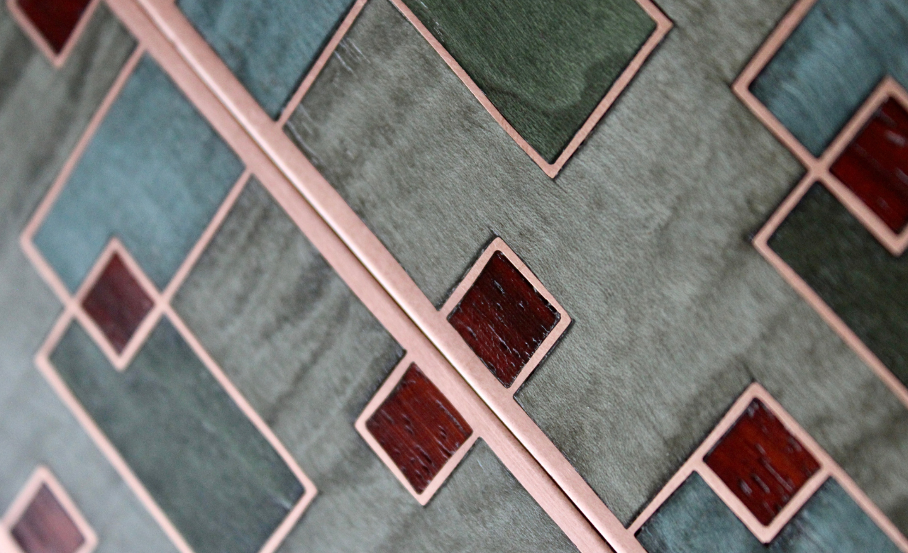 Composition géométrique en bois teinté gris et vert, cuivre et inserts rouge sombre. Exemple d’un échantillon contemporain pour des projets haut de gamme.