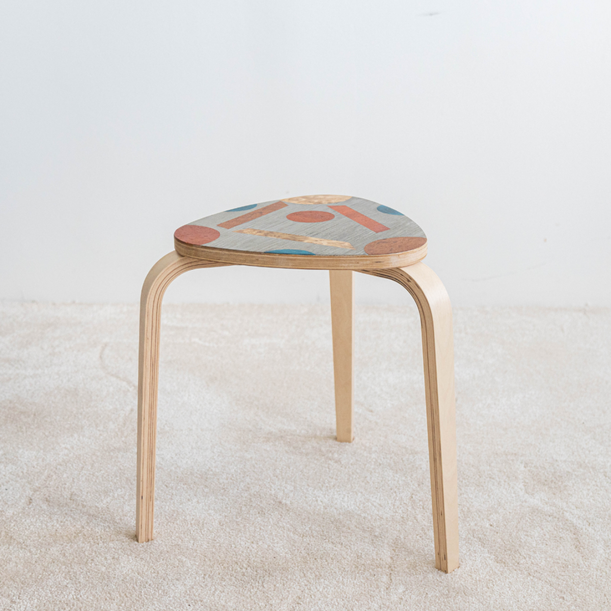Tabouret en bois décoré avec des motifs géométriques colorés, conçu lors de l’atelier tabouret en marqueterie bois. Une création artisanale unique.