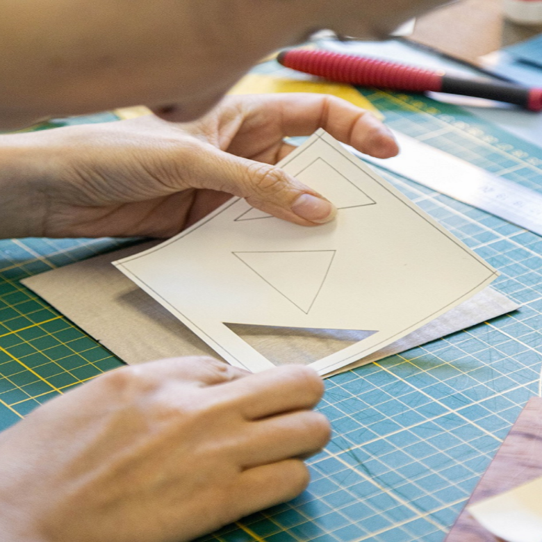 Étape de découpe des motifs géométriques pour créer un dessous de verre en marqueterie bois. Une activité de précision enseignée lors de l’atelier.