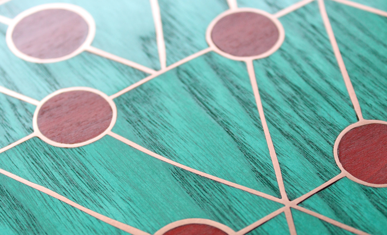 Motifs géométriques en marqueterie cloisonnée, bois teinté turquoise, incrustations rouges et lignes de cuivre. Idéal pour des intérieurs modernes et raffinés.