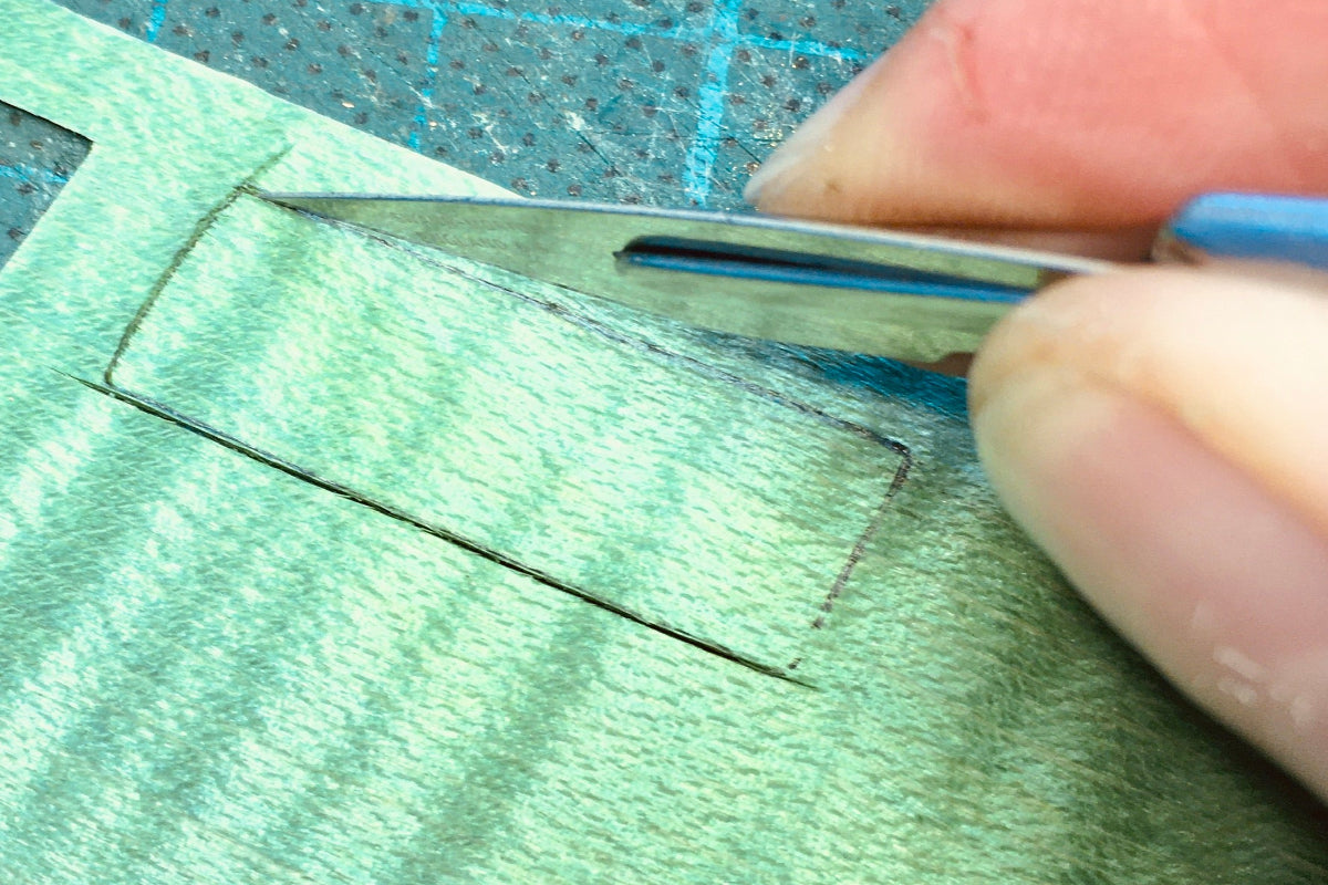 Geste de découpe précise d’un placage de bois vert au scalpel, réalisé lors d’un stage de marqueterie à l’Atelier Nathalie Melon à Nancy.