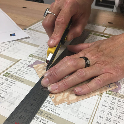 Geste de découpe manuelle de placages de bois au cutter pendant un stage de marqueterie à l’Atelier Nathalie Melon à Nancy.