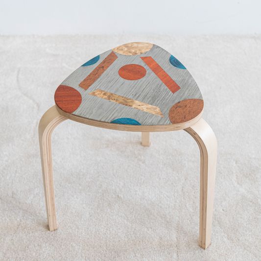 Tabouret en bois décoré avec des motifs abstraits et colorés en marqueterie, conçu lors de l’atelier tabouret. Une réalisation artisanale unique et personnalisée.