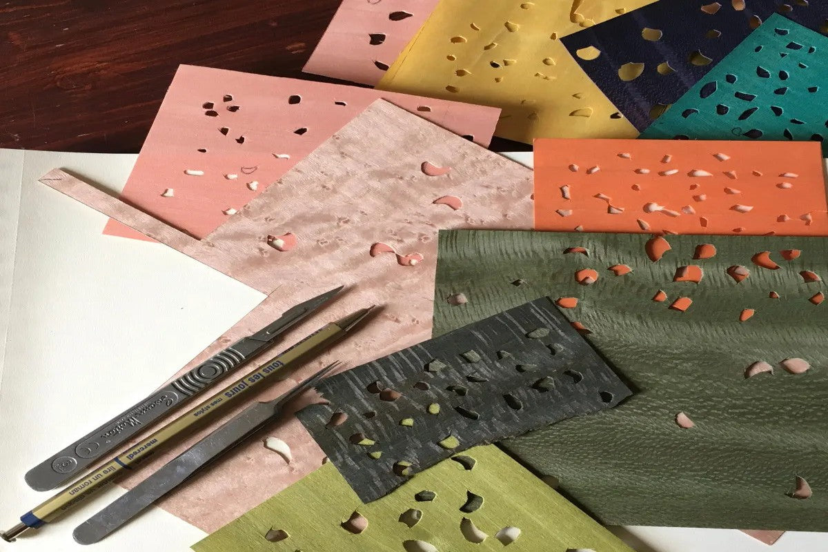 Feuilles de placage bois colorées et outils de découpe utilisés pour les créations en marqueterie à l’Atelier Nathalie Melon à Nancy