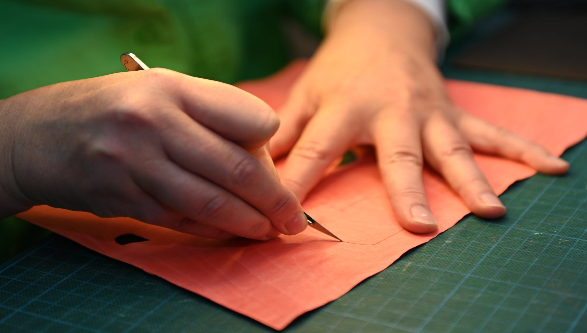 Mains d’artisane découpant une pièce de placage bois à la main dans l’atelier Nathalie Melon, spécialisé en marqueterie cloisonnée bois et métal à Nancy.